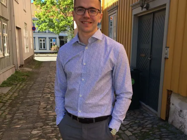 Sebastian Eriksson utendørs ved små trehus i gammlebyen