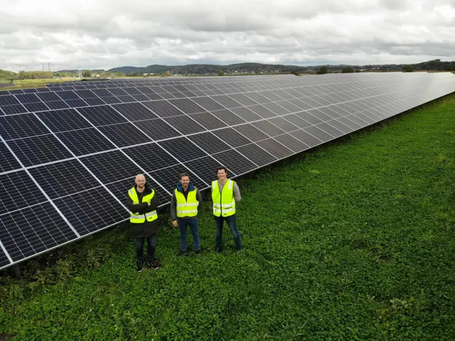 3 menn foran solceller på bakken