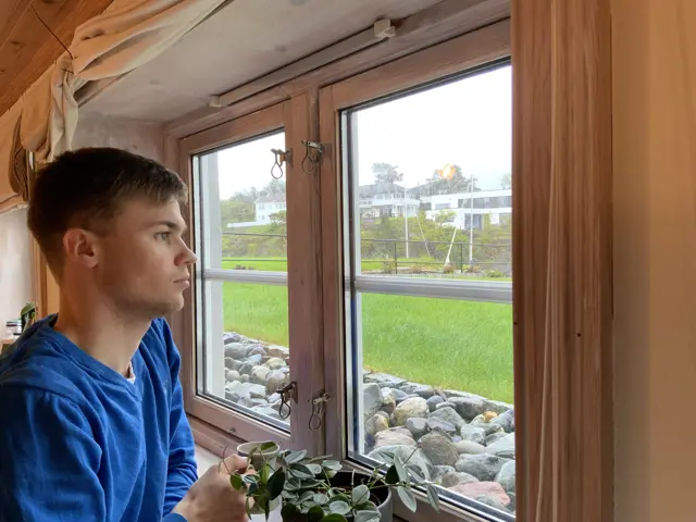 Erlend med kaffekopp ser ut vindu