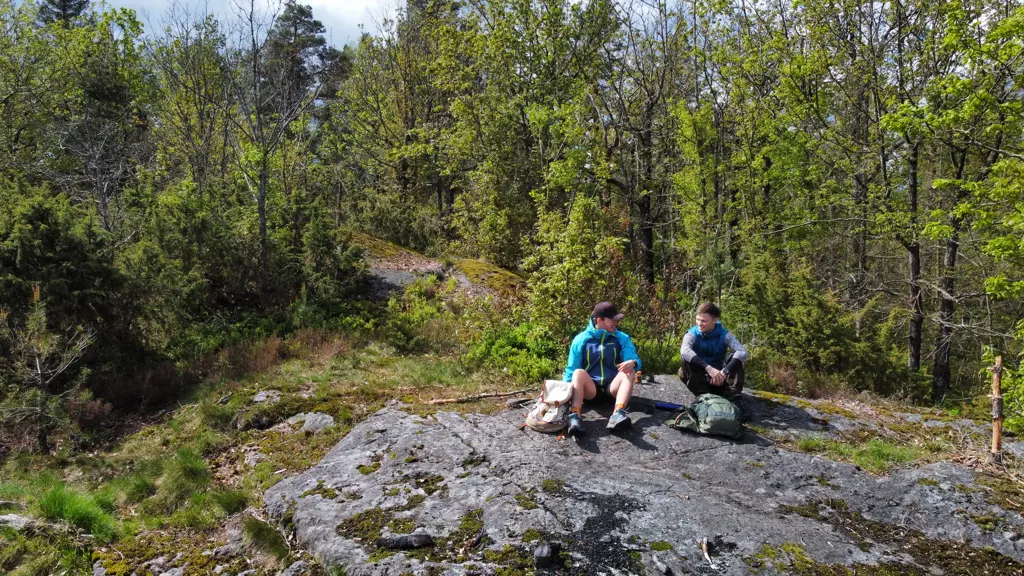 Erlend og en person til, sitter på en stein i skogen mens de går tur