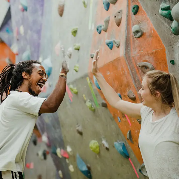 To personer som gir high five foran klatrevegg