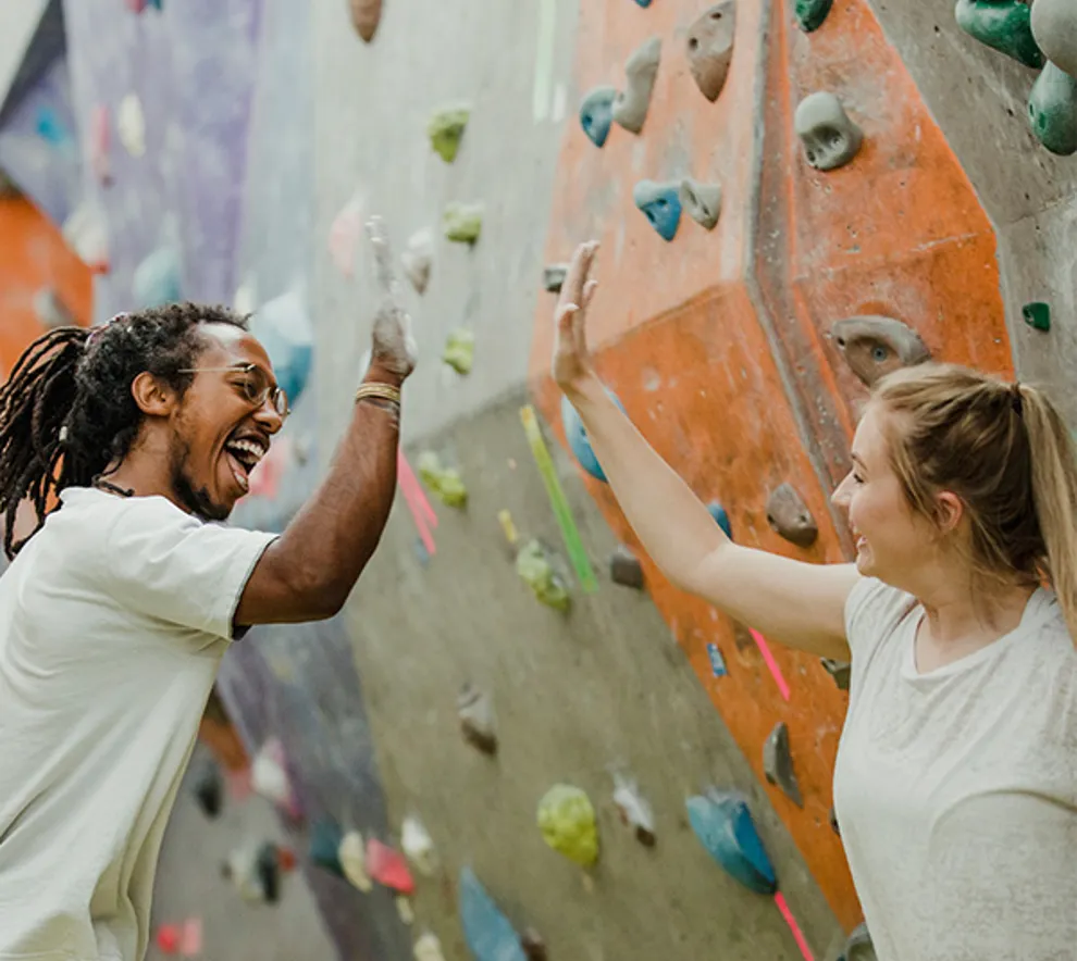 To personer som gir high five foran klatrevegg