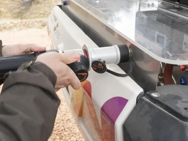Nærbilde av en hånd som holder en hydrogenlader og fyller en bil