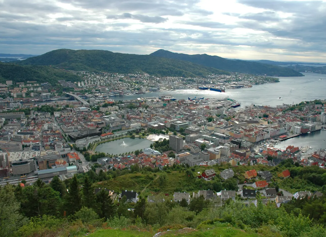 Oversiktsbilde av Bergen med byen med Lille Lungegårdsvannet med vannfontene nærmest og havet og fjell i bakgrunn