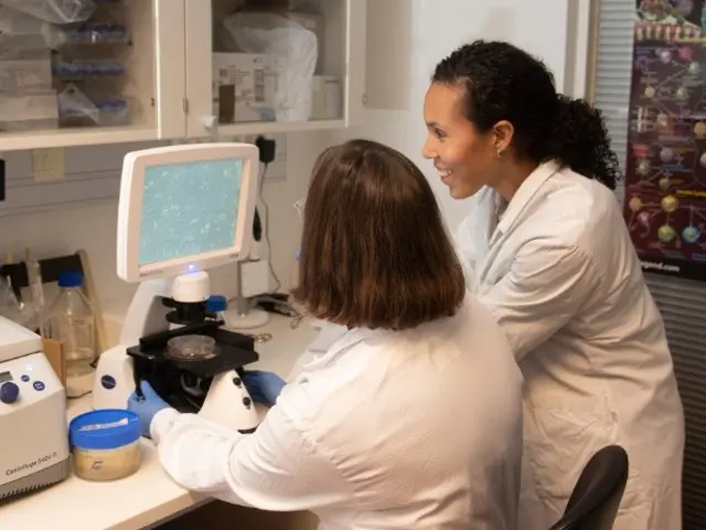 To kvinner i en lab sitter og ser på en skjerm