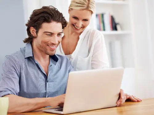 Par ser på en laptop og smiler