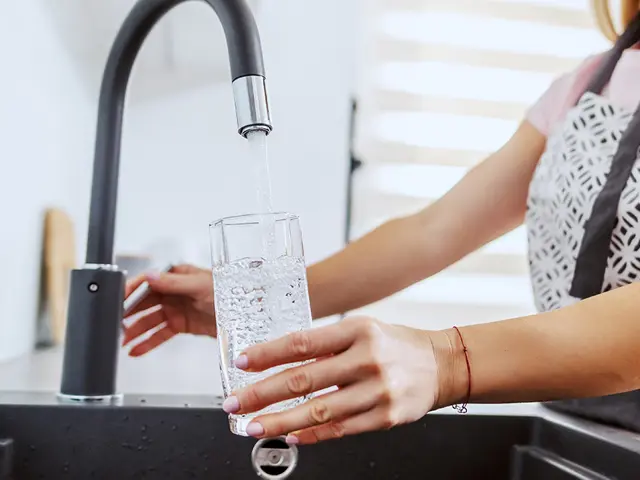 En person fyller et glass vann fra springen 