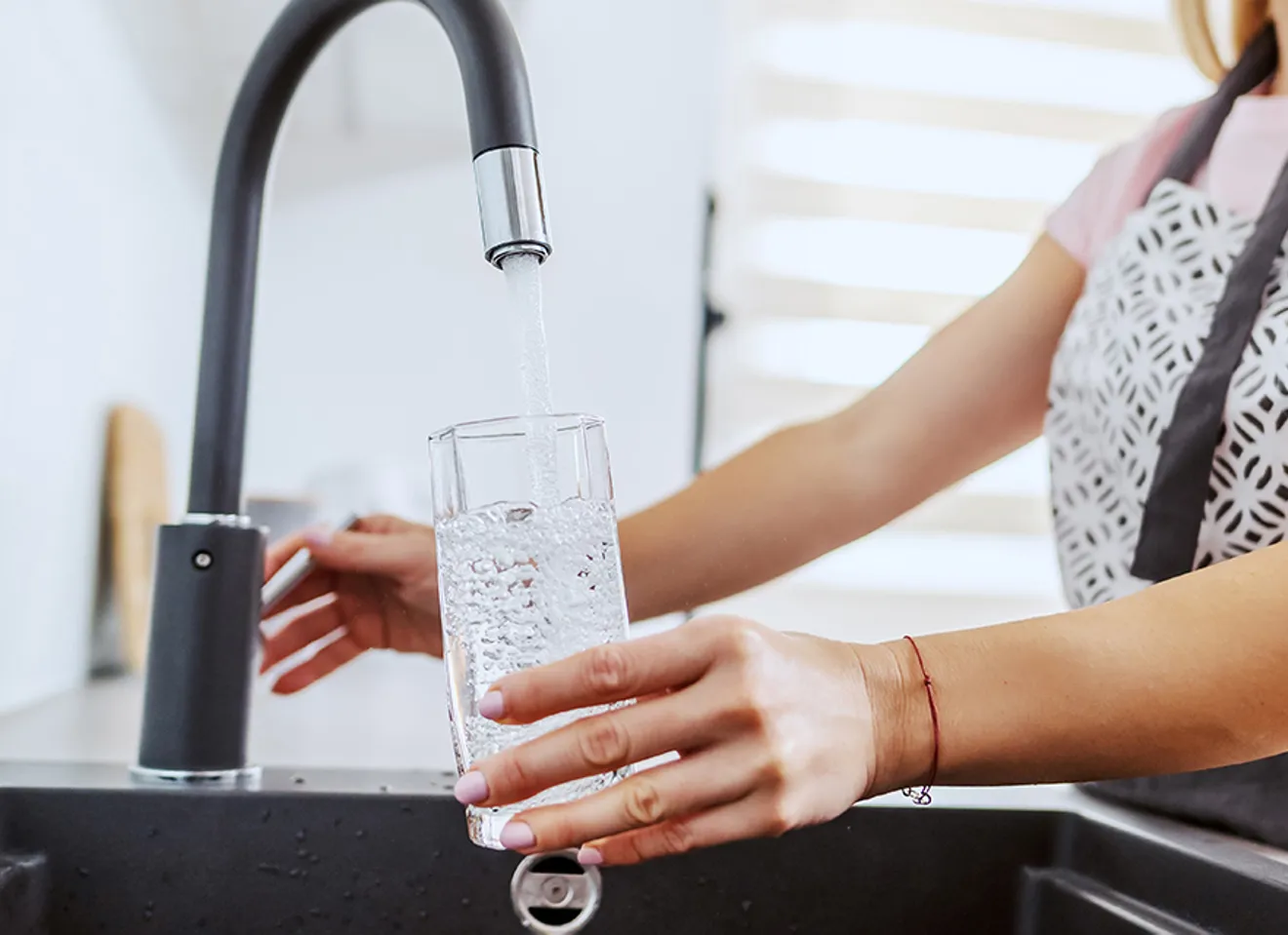 En person fyller et glass vann fra springen
