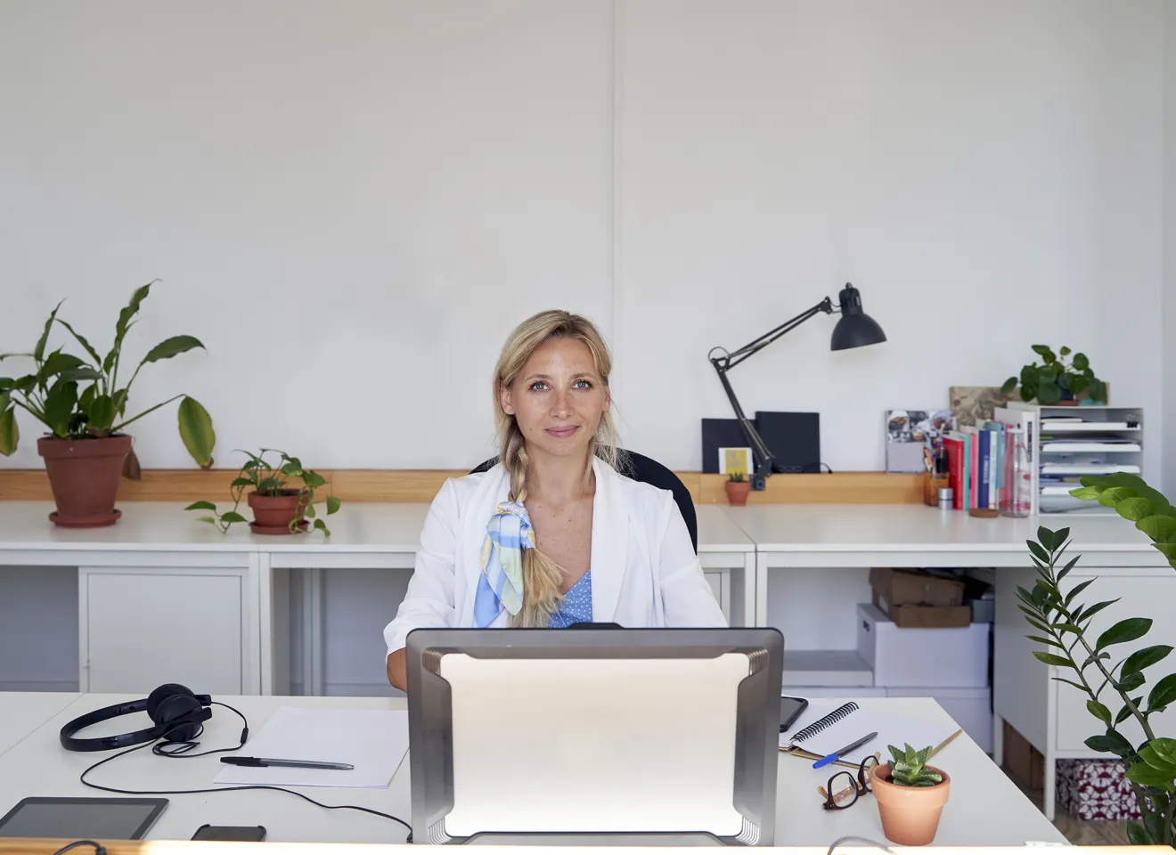 Illustrasjonsbilde av en ung kvinne som sitter på kontoret og smiler til kamera