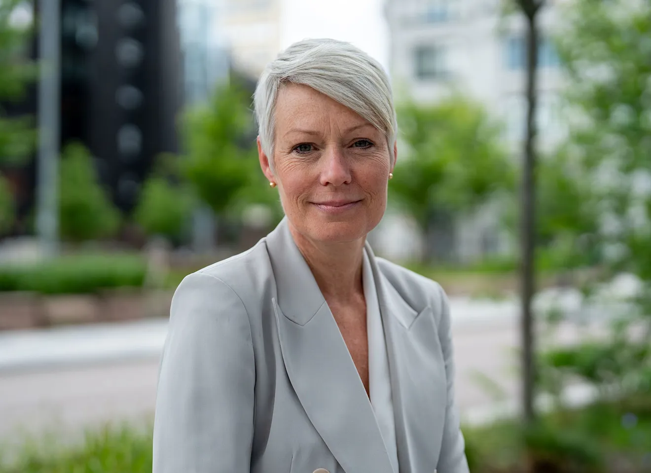 Line Henriette Holten, nøytralt ansiktsuttrykk, grå jakke, grønne blader i bakgrunnen