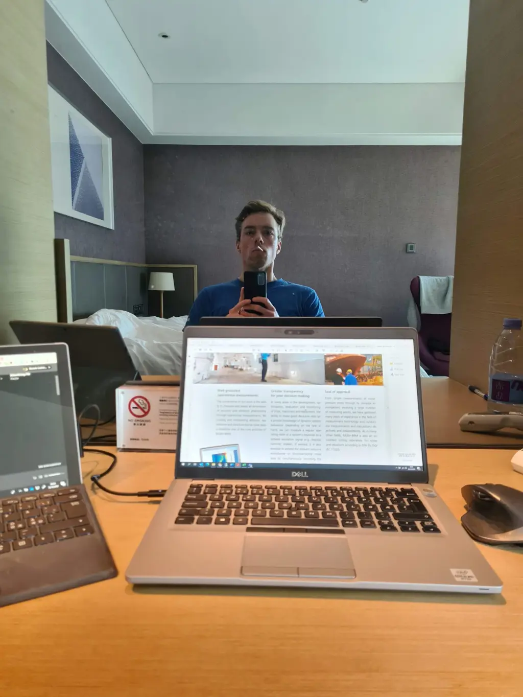 Selfie i speilet med laptop på hotelbordet