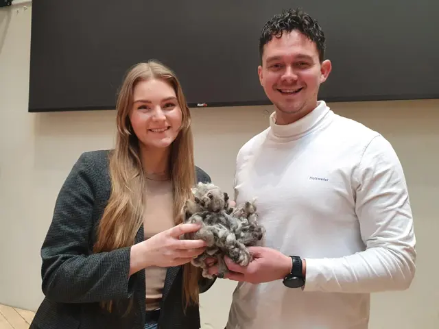 Kvinne og mann holder en klump med saueull