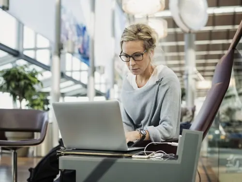 Kvinne på jobbreise som jobber mens hun sitter på flyplassen