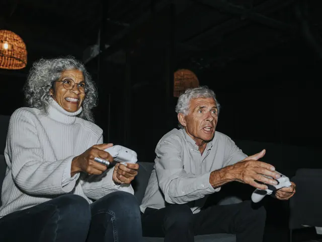 to eldre mennesker koser seg med  dataspill