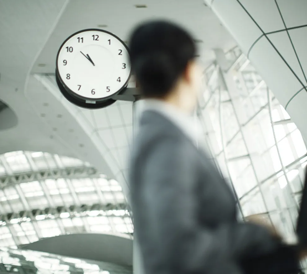 En mann i dress som går forbi en klokke