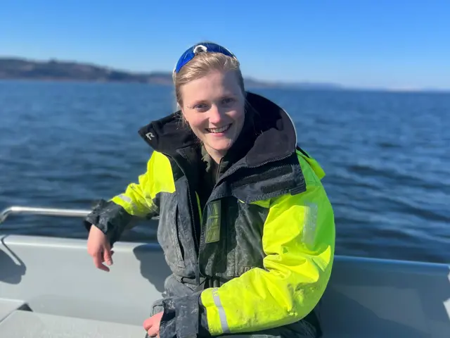 Kvinne sittende ved havet