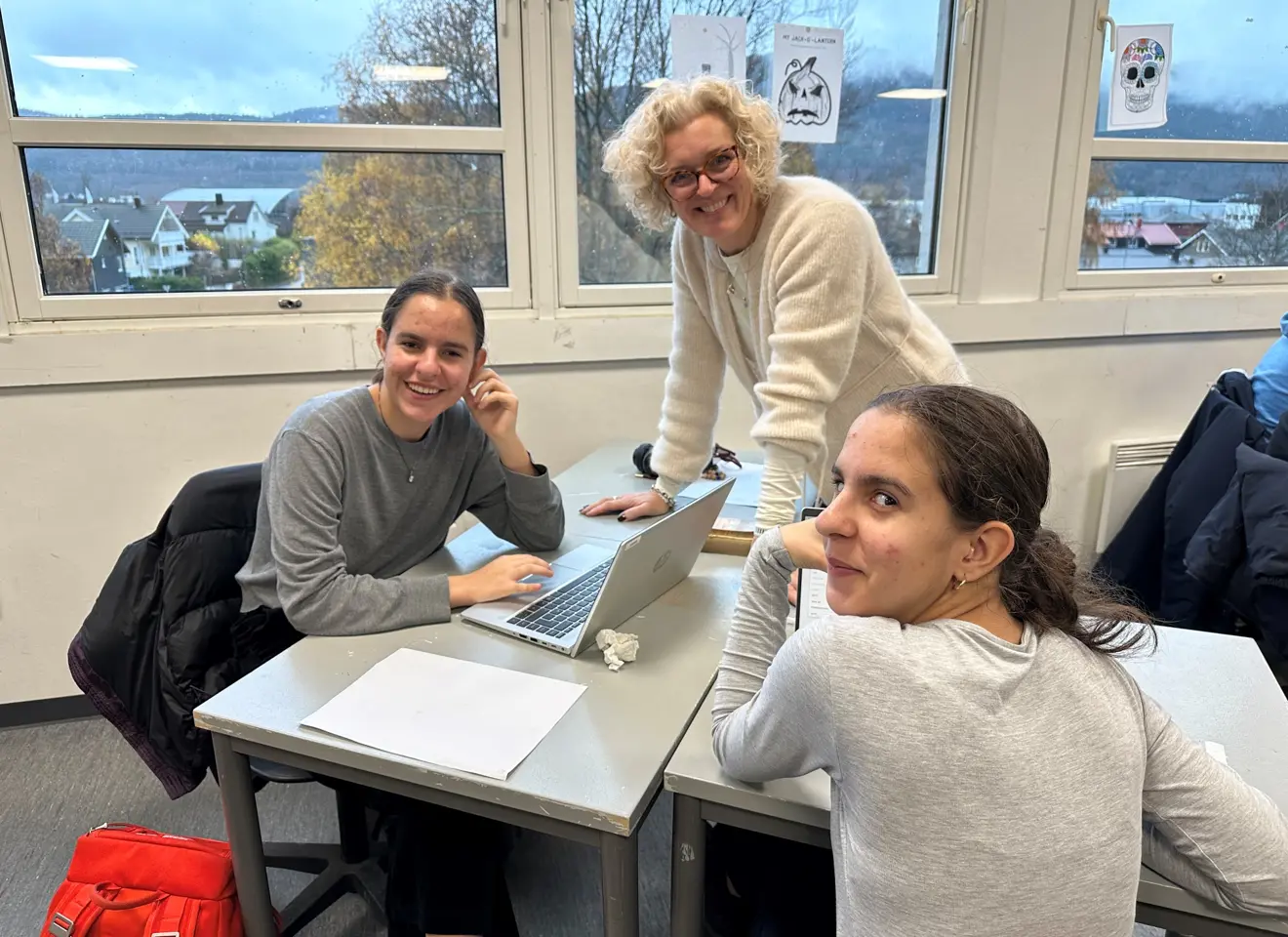 Lærer og 2 elever mot vindu bak