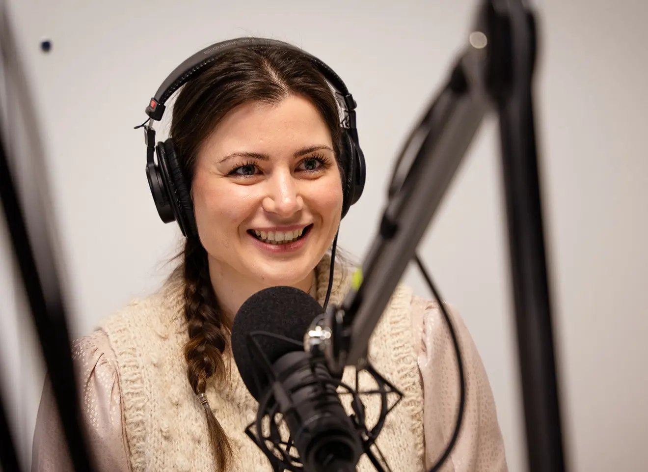 Visepresident Elisabet Haugsbø sittende i podkaststudio med hodetelefoner, pratende i en mikrofon.