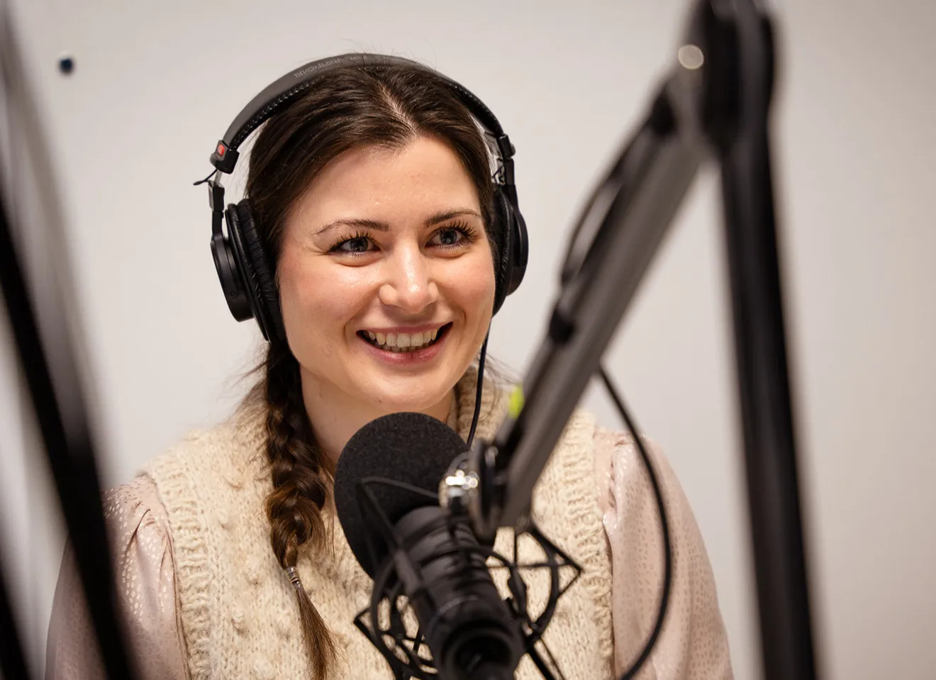 Visepresident Elisabet Haugsbø sittende i podkaststudio med hodetelefoner, pratende i en mikrofon.