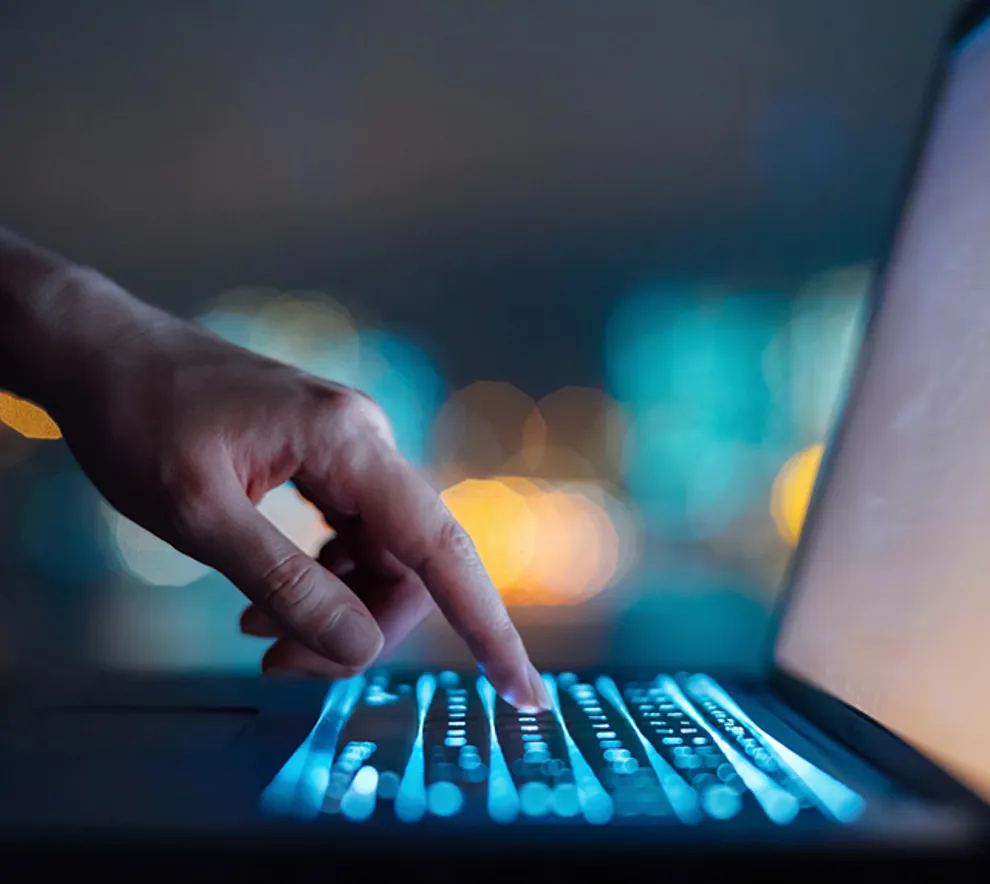 En som trykker på mørk PC med selvlysende tastatur