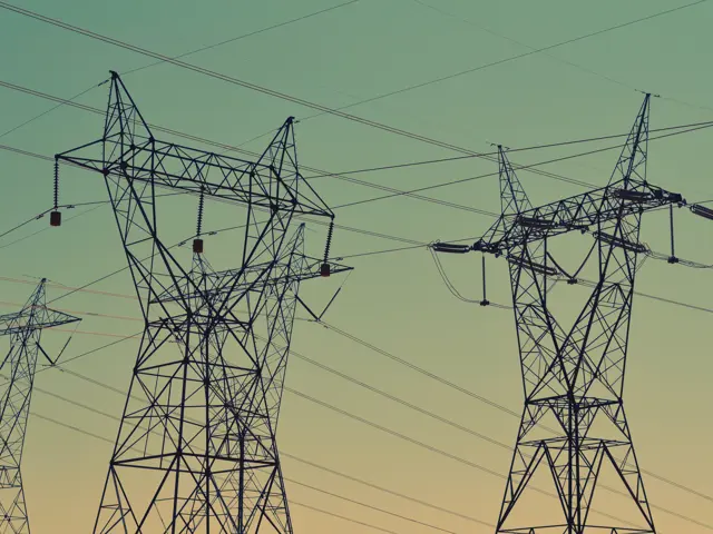 Nærbilde av flere strømmaster i solnedgang