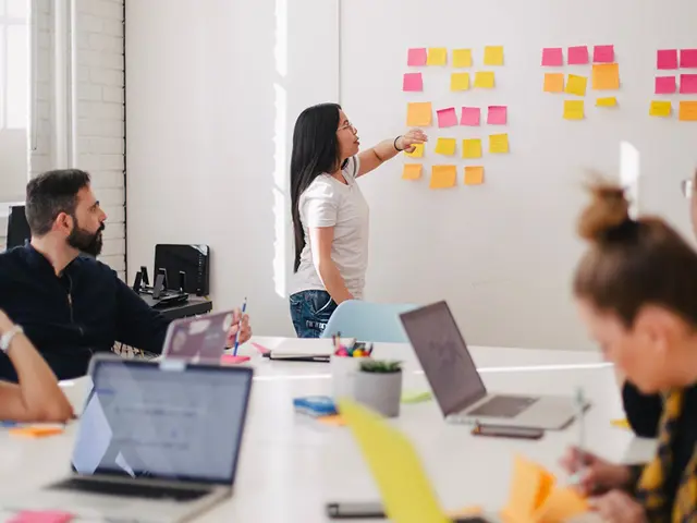 Illustrasjonsbilde av en gruppe ansatte sittende og se på en ung kvinne foran et whiteboard