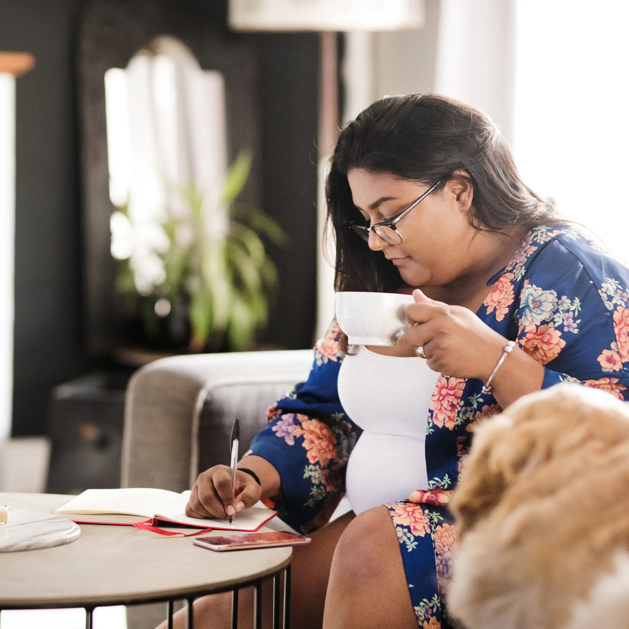 Illustrasjonsbilde av en kvinne med kaffekopp som skriver i et notatbok