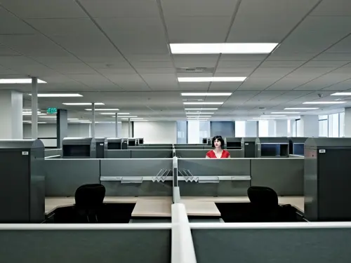 Illustrasjonsbilde av én kvinne stående alene i et stor kontorlandskap