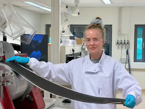 Kvinne i labfrakk holder et flak av mangan