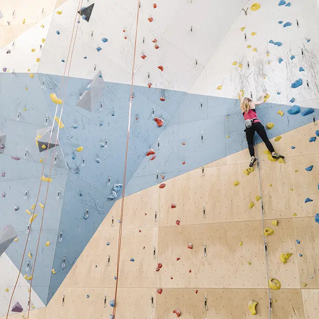 Jente som klatrer i klatrevegg