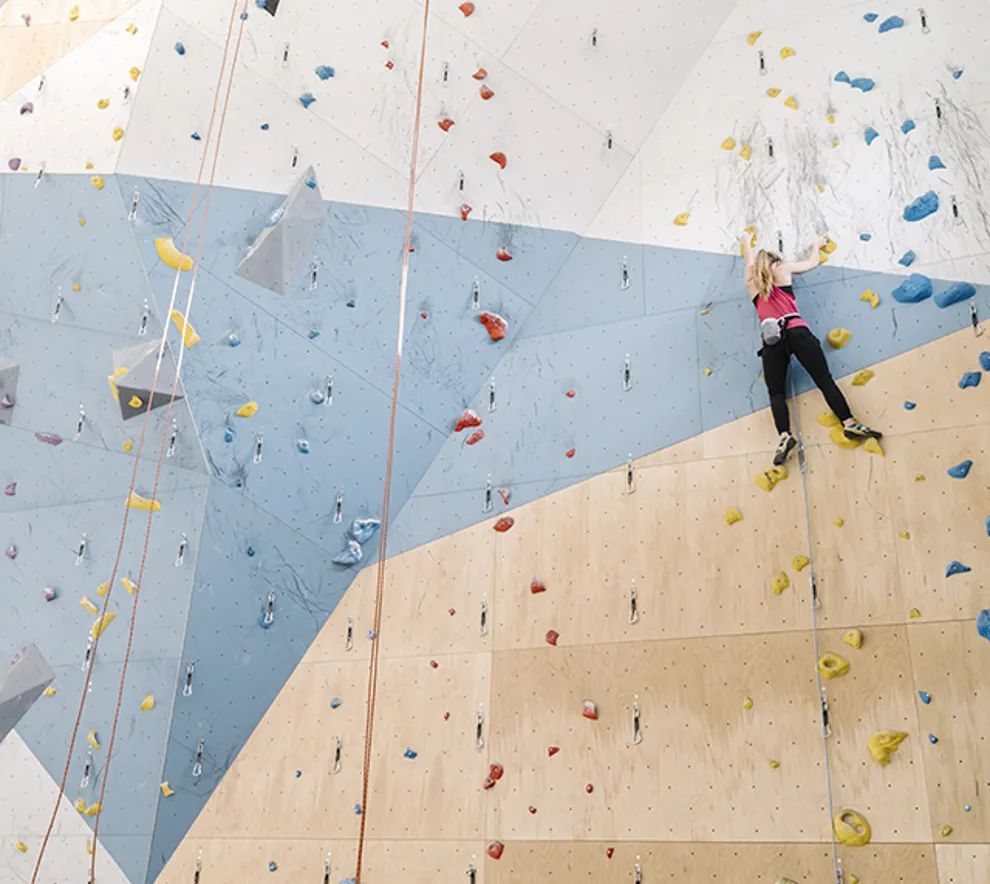 Jente som klatrer i klatrevegg