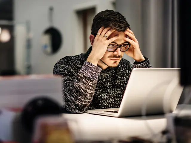 Ung person som sitter foran en datamaskin og tar seg til hodet