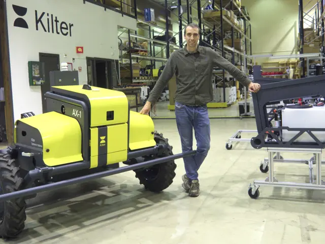 Mann i verkstedhall med gul robot