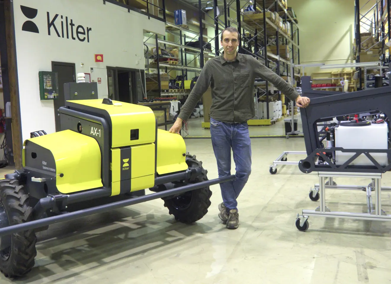 Mann i verkstedhall med gul robot