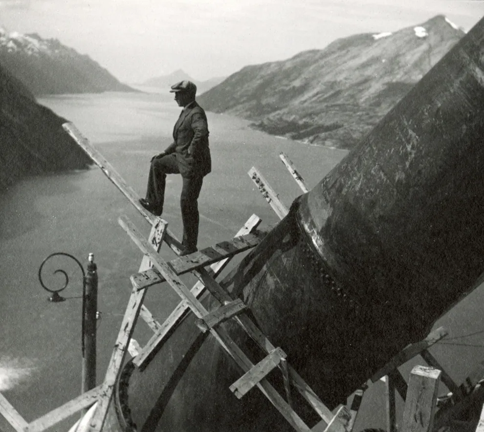 Mann står på rekkverk under byggingen av rørgatene i Glomfjord i 1918