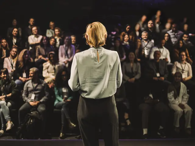 Kvinne som snakker til forsamling