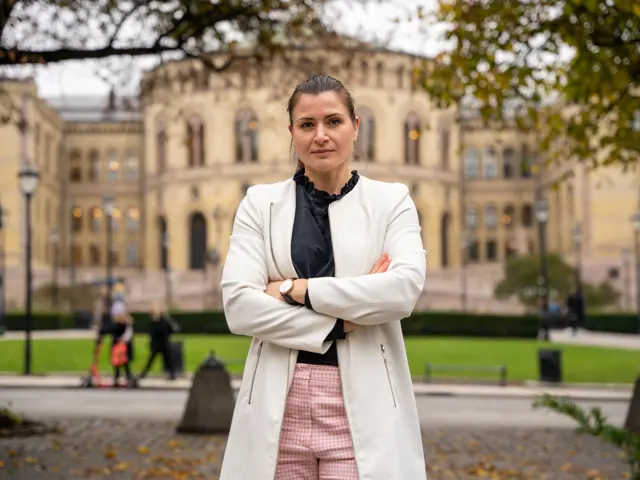 President Elisabet Haugsbø, armene i kors, alvorlig, hvit jakke, foran stortinget, høst 