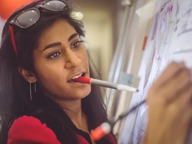 ung kvinne skriver på tavle med tusj i munnen