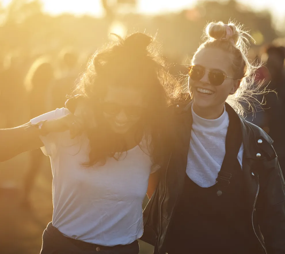 To unge studenter koser seg på festival i solnedgang