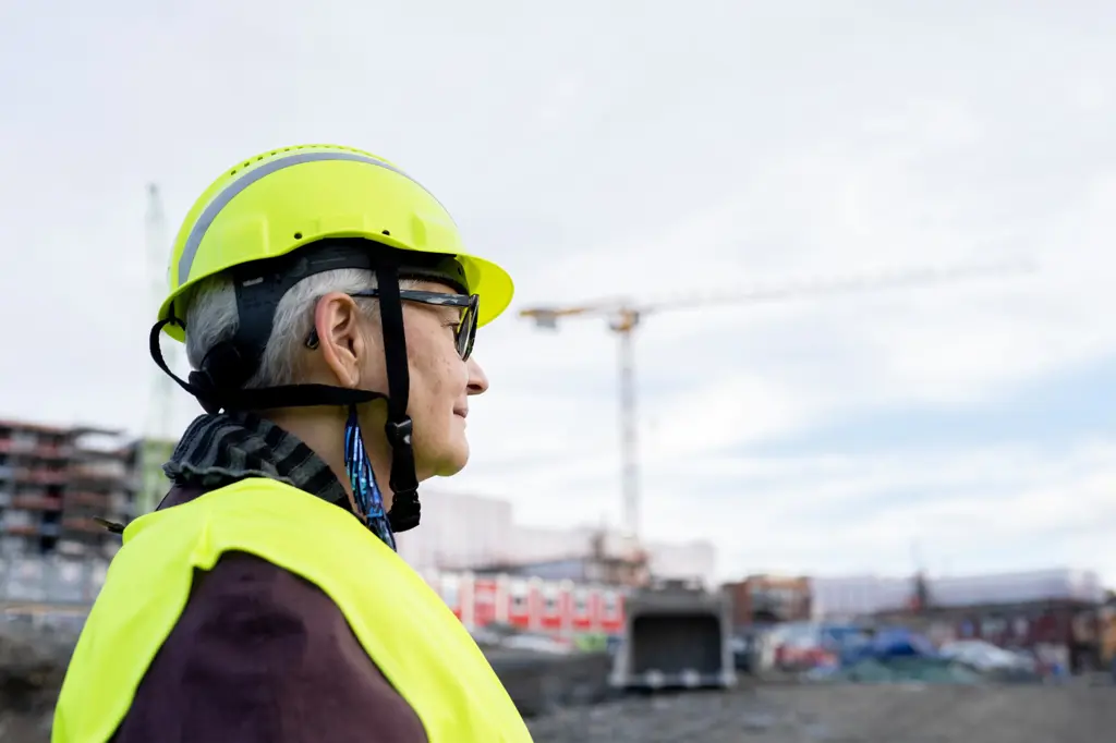 Kvinner med hjelm ser mot byggeplass