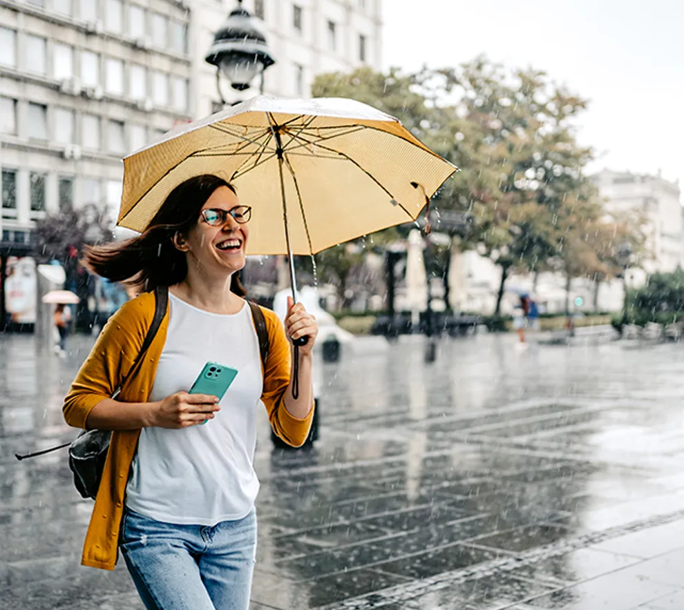 Kvinne med paraply går over bytorg