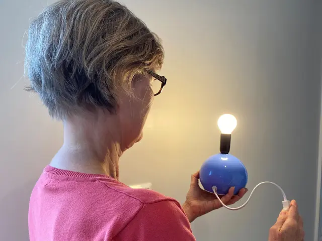 En voksen kvinne slår av en lyspære