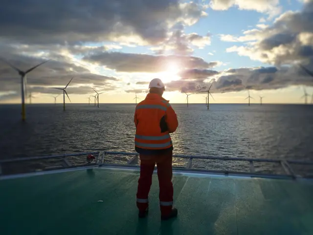 Arbeider på plattform som står omgitt av hav vindmøller