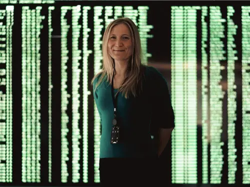 Portrett av Aurora Voje foran en skjerm med grønn kildekode