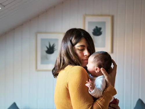 Kvinne holder en gråtende baby på armen
