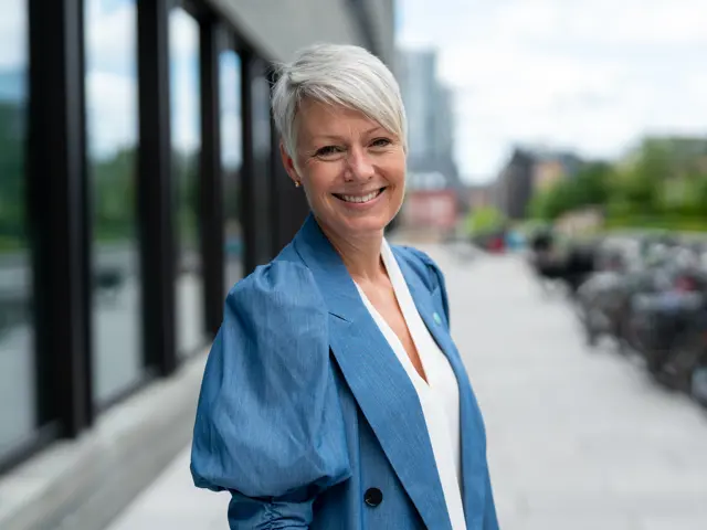 Line Henriette Holten portrettbilde utendørs, blå jakke, smiler