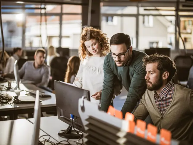 Illustrasjonsbilde av en mann som viser en ung mann og en ung kvinne noe på data