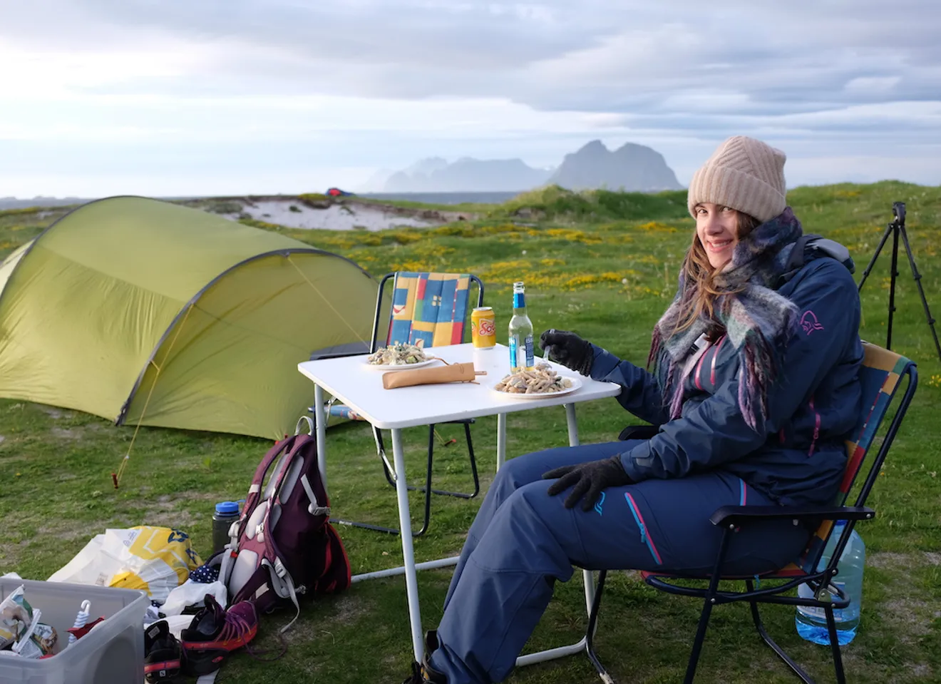 Mari Henanger sitter på en campingstol bak et telt med utsikt over havet