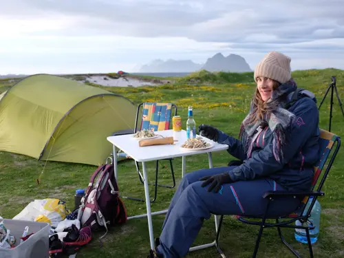 Mari Henanger sitter på en campingstol bak et telt med utsikt over havet