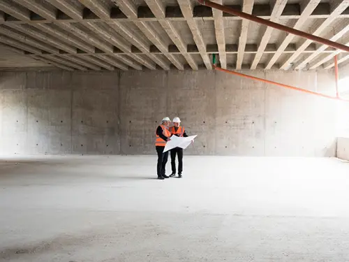 to arbeidere i et stort lokale i betong